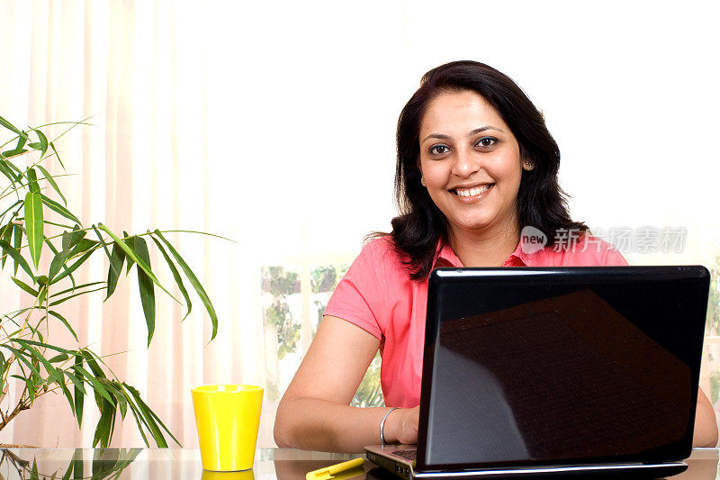 一位愉快的印度女商人正在使用笔记本电脑