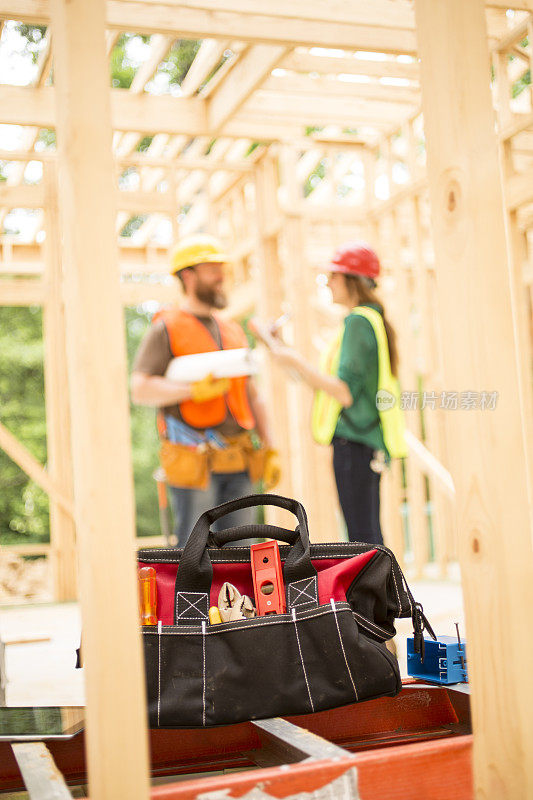 建筑工人在工地上拿着工具包。