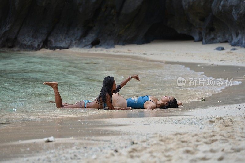 两个美丽的女人躺在异国情调的海滩上
