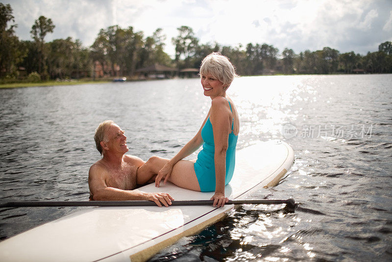 微笑的老年夫妇与桨板在海上