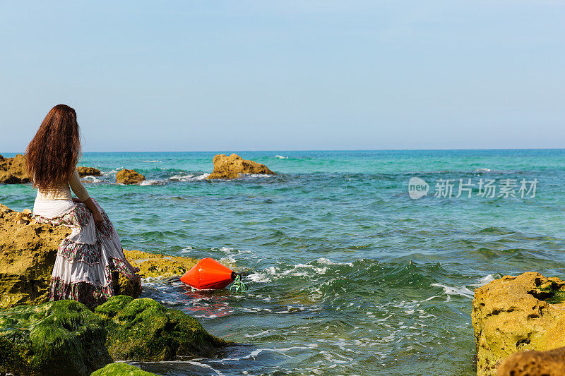 坐在海边岩石边沉思的女人