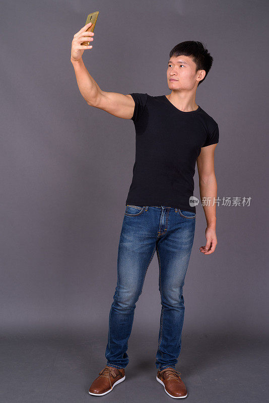 年轻的中国男子穿着黑色衬衫，映衬着灰色的背景