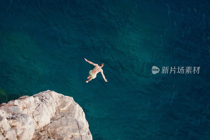 年轻人从悬崖上跳入大海。