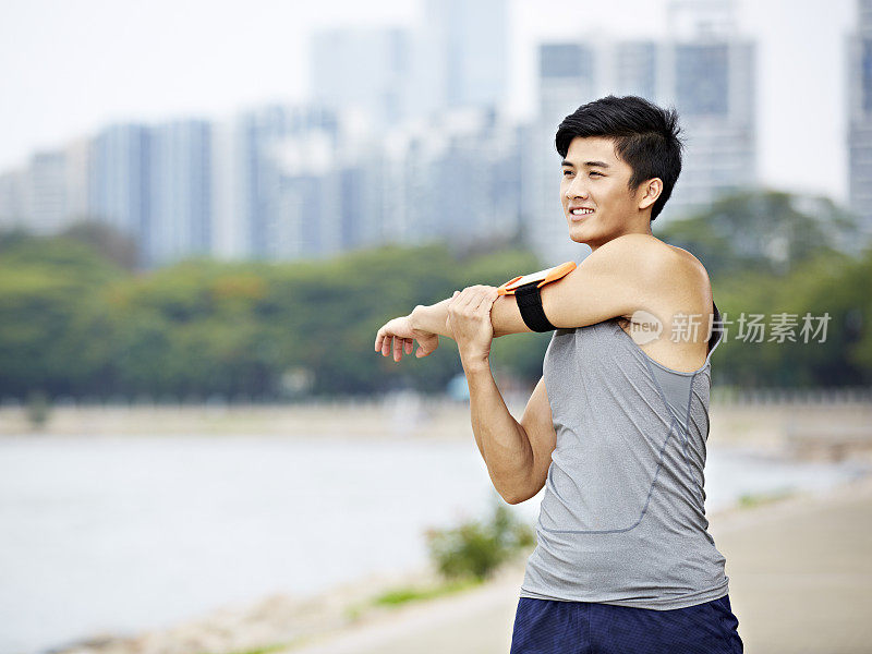 年轻的亚洲慢跑者在公园里伸展手臂