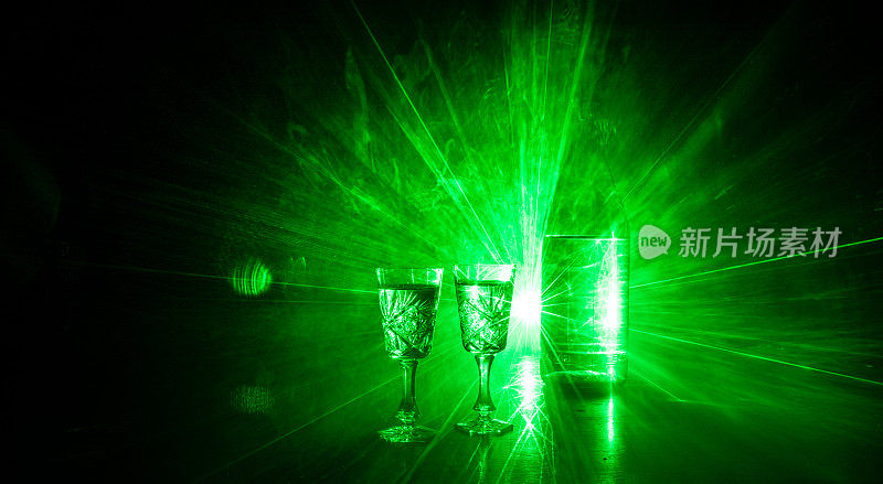 两杯伏特加与瓶在黑暗雾俱乐部风格的背景与发光灯(激光，Stobe)多颜色。会所饮品主题装饰。空的空间
