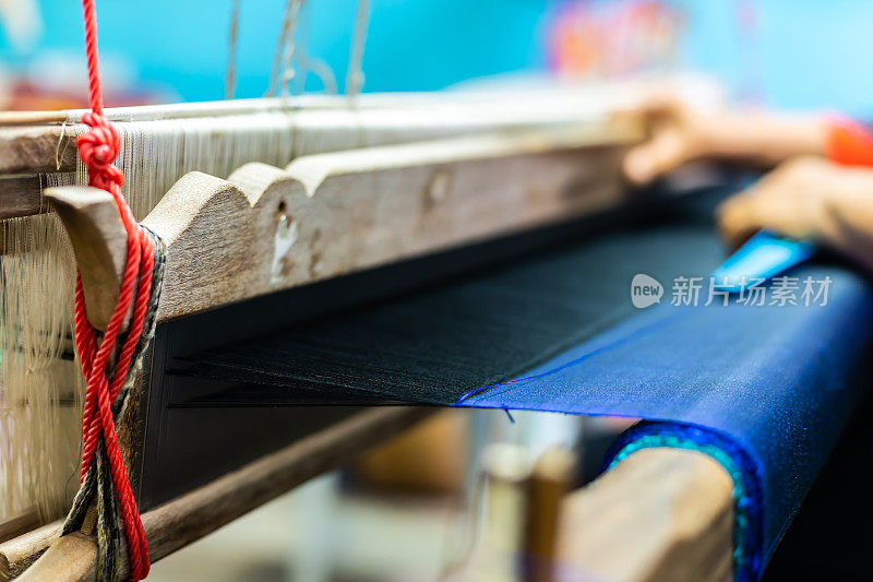 织机上的丝绸和泰国传统丝绸的特写。用于自制丝绸纺织品的织布机