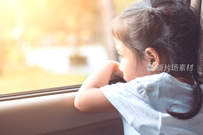 可爱的亚洲小女孩坐在车里，看着窗外