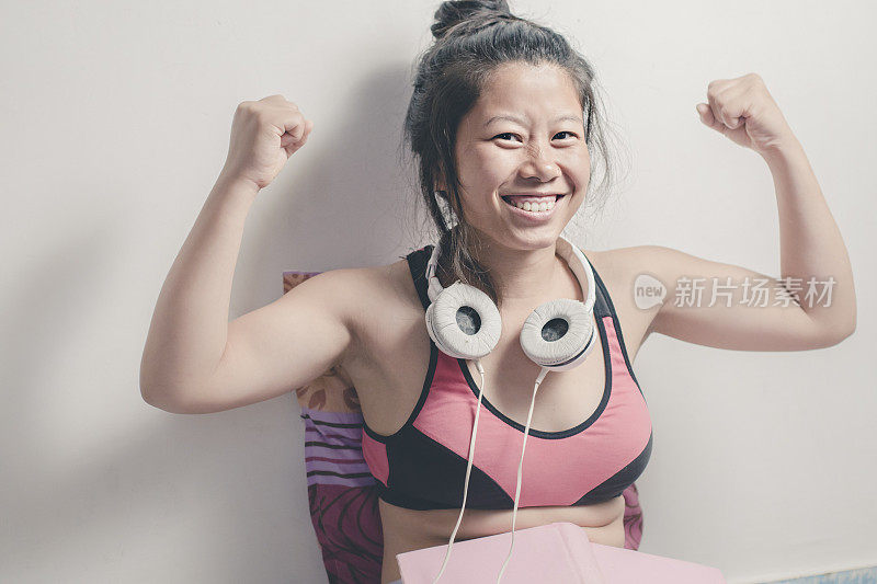 快乐的亚洲年轻女子展示她的肌肉。
