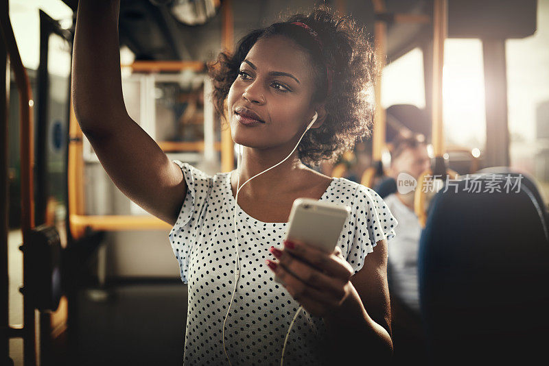 年轻的非洲妇女在公共汽车上听音乐