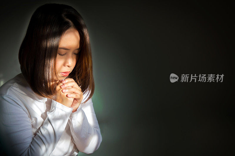 中年亚洲妇女坐着祈求祝福。用暗色和浅色效果从内部看起来像气场。