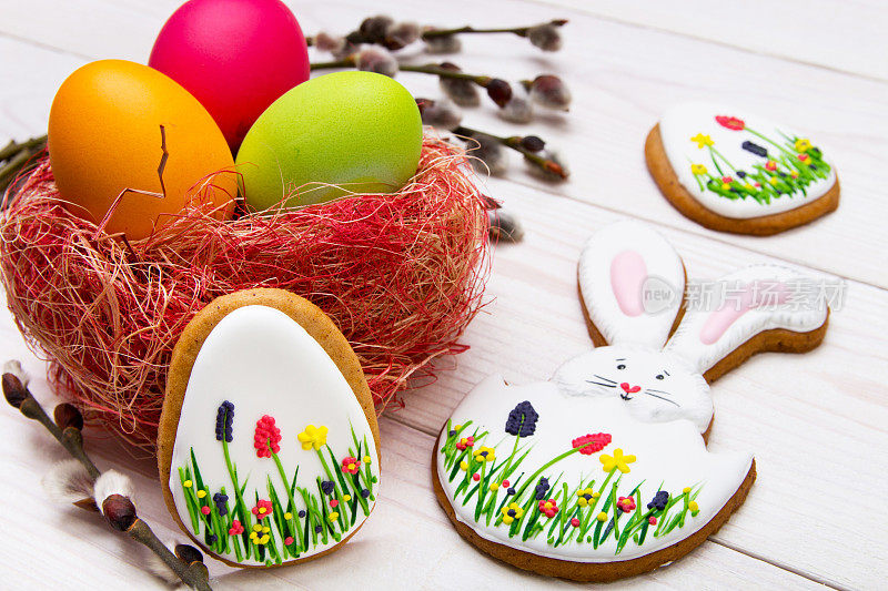 姜饼复活节以白色的木头为背景，画上彩蛋和柳枝。复活节兔子和鸡蛋，姜饼