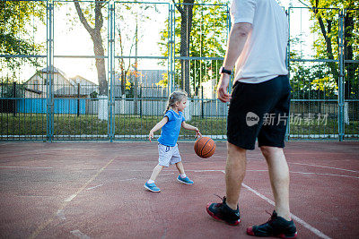 年轻的千禧一代父亲和他的小女儿打篮球