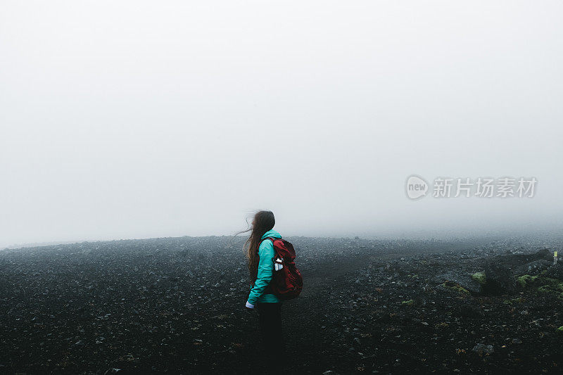 女人背包徒步旅行，虽然火山景观和风在冰岛无处