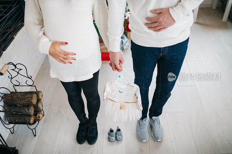 丈夫抱着婴儿的鞋子和衣服的孕妇