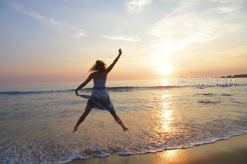 日落时分，一个女人在海滩上跳起来