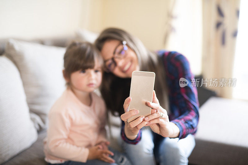 一个年轻女子在家里和她的小女儿自拍