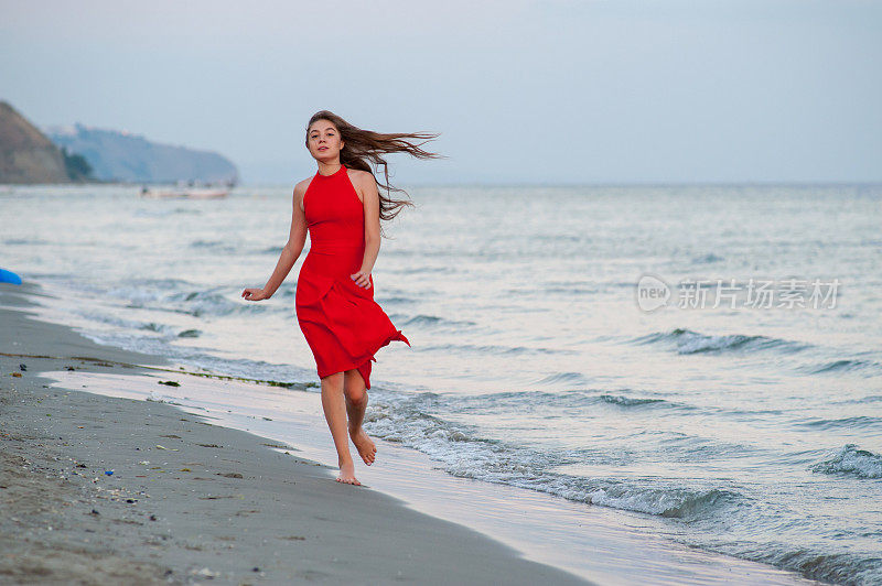 穿红衣服的年轻女子在海滩上跑步