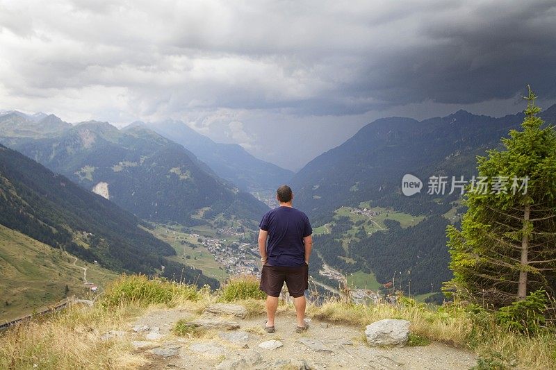 一个成熟的男人站在瑞士圣哥达山口。