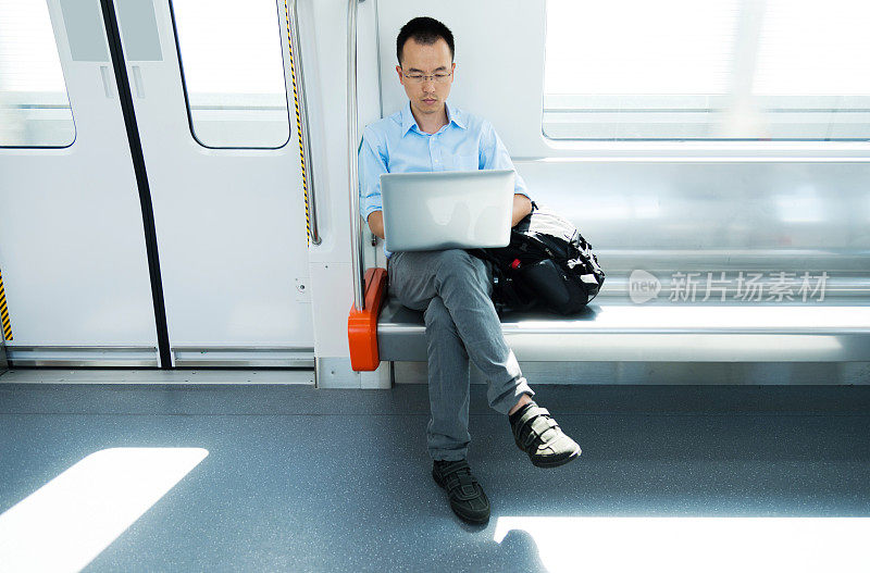 在地铁上使用笔记本电脑的商人