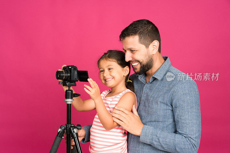 父亲向他可爱的小女儿展示如何使用相机