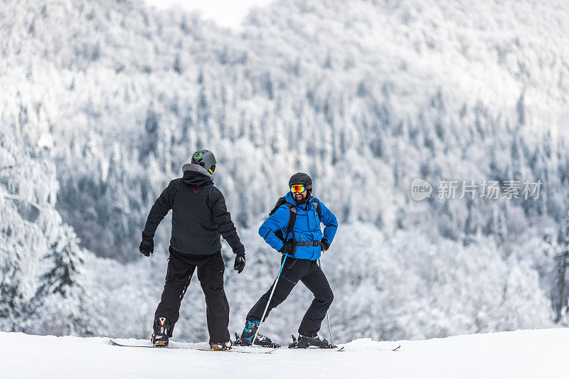 快乐的滑雪者和他的朋友在冬日滑雪板上聊天。