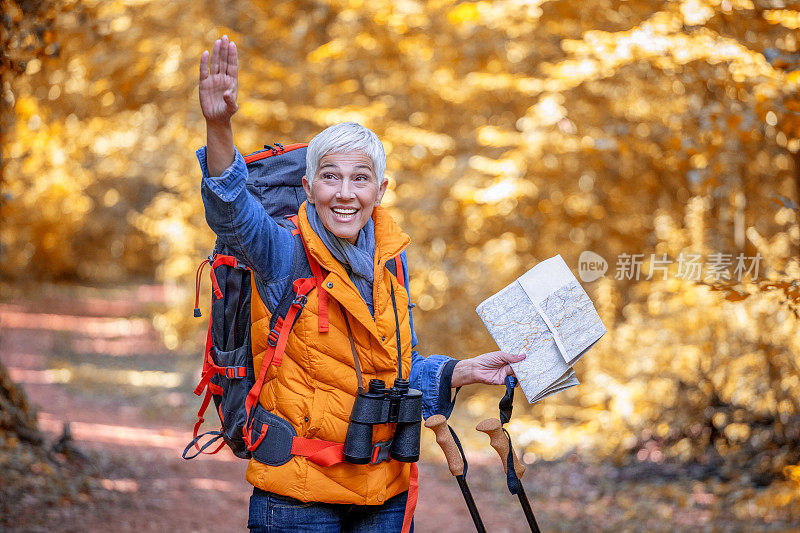 美丽成熟的老年妇女在60岁早期徒步秋天的森林