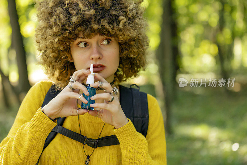 年轻女子在户外用鼻喷剂治疗过敏