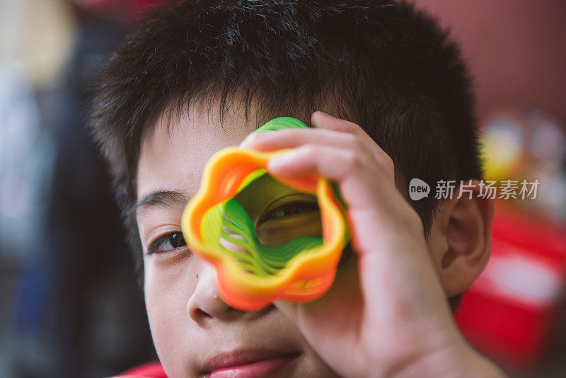 亚洲男孩玩花形弹簧彩虹