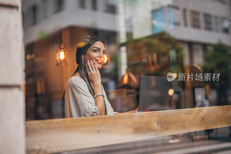 一位女士在市中心的咖啡馆用笔记本电脑