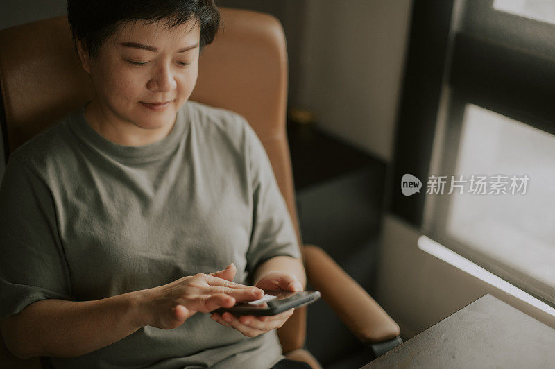 一位亚洲华人女性在房间里用完手机后擦拭手机