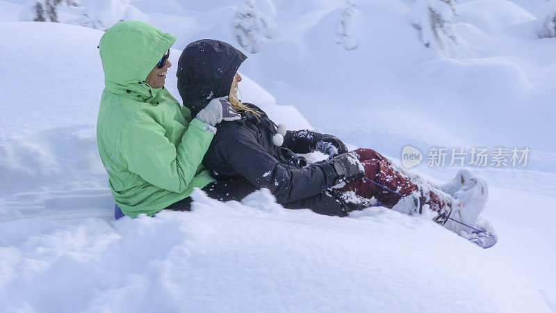 母女俩滑着雪橇滑下山坡