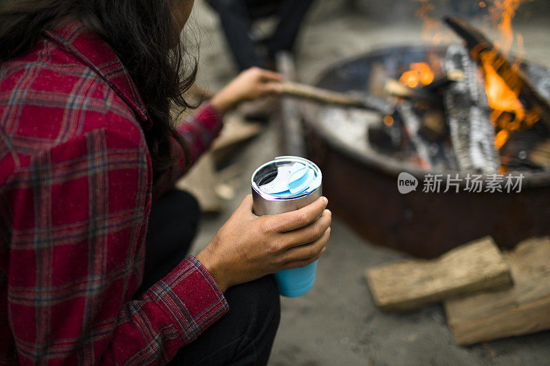 篝火边拿着咖啡杯的女人