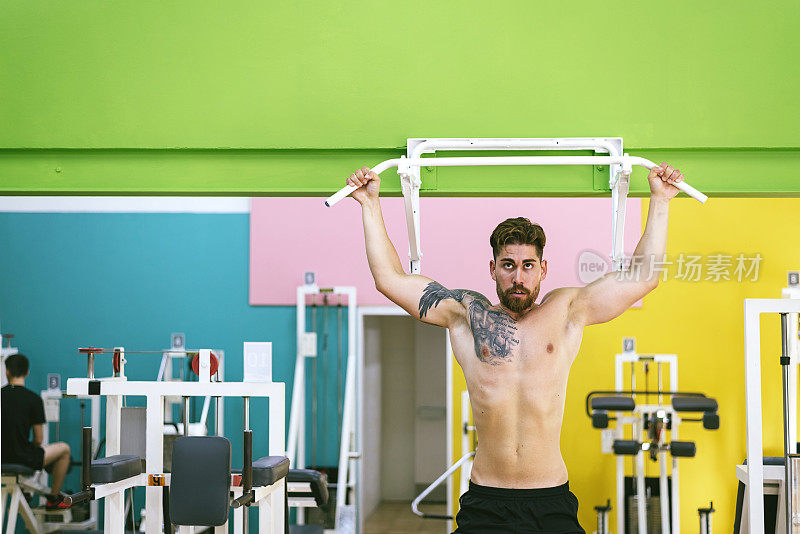 肌肉男在健身房做引体向上，在健身俱乐部锻炼。