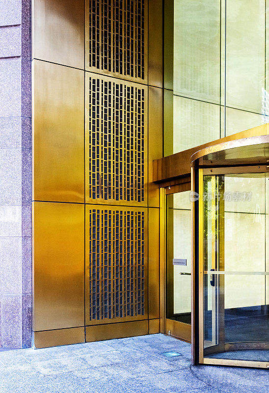 现代办公大楼外观采用金色旋转门入口。街道上的观点。