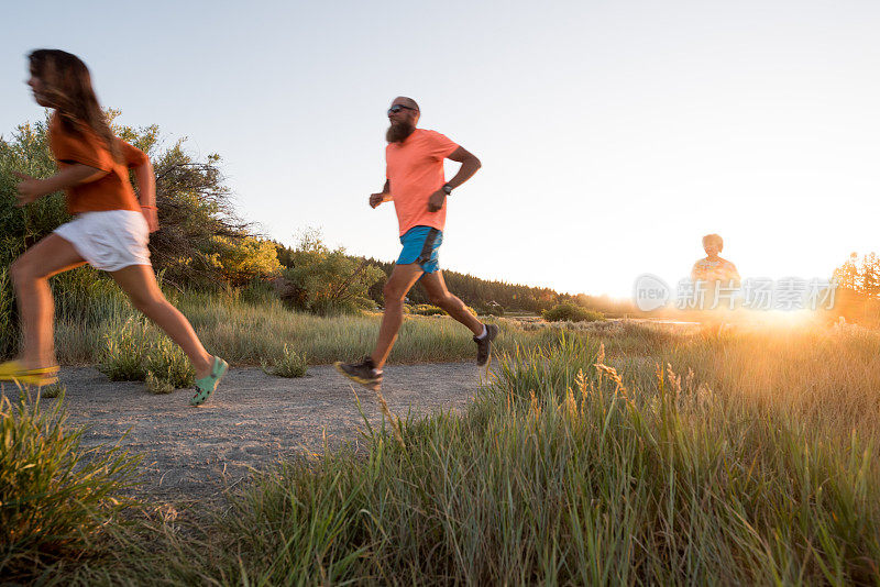 活跃的家庭在日落时跑步、玩耍和骑自行车