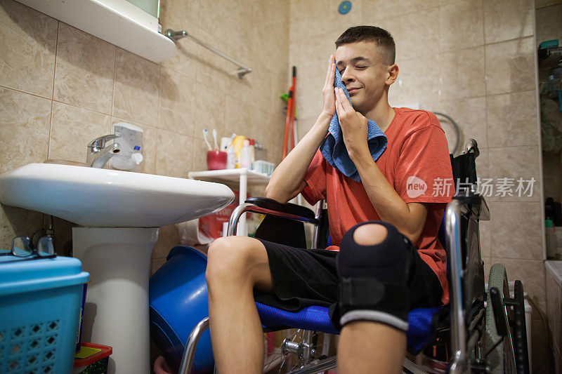 一个坐在轮椅上的青少年在浴室里刷他的牙齿和洗脸