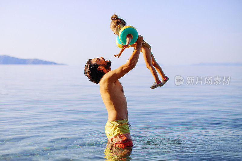英俊的父亲和他的女儿在海里跳