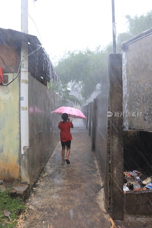 一个小女孩在倾盆大雨中带着雨伞。