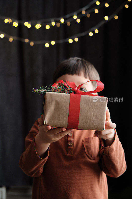 4-5岁的孩子拿着礼物盒在黑暗的背景为圣诞节庆祝