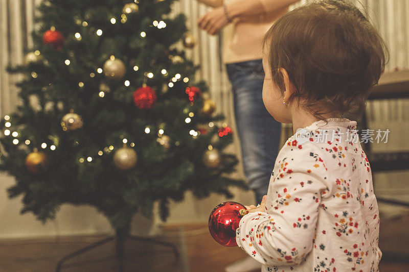 小女孩看着妈妈装饰圣诞树
