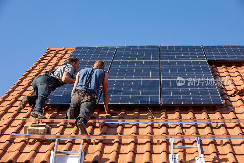 工人们正在屋顶上安装太阳能电池板