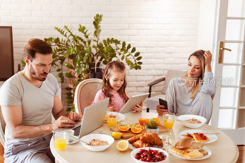 忙碌而不联系的家庭在餐桌上使用科技