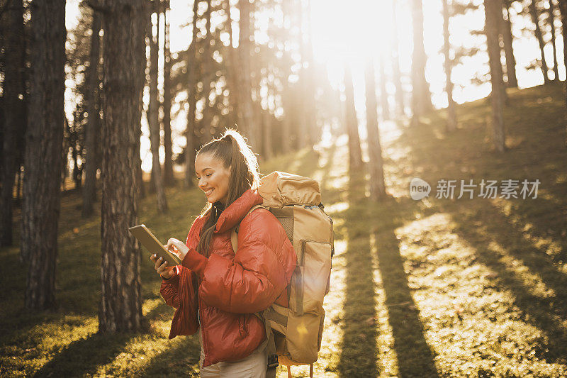 年轻的微笑的女人徒步在自然的山脉和连接的数字平板电脑