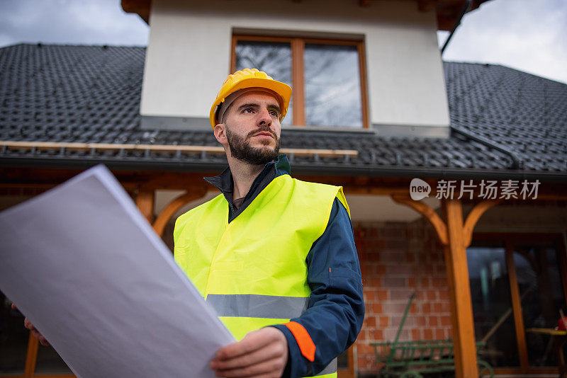 白人建筑工人拿着蓝图环顾四周