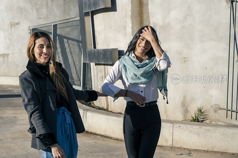 两个美丽快乐微笑的女人走过一个城市。快乐的概念。