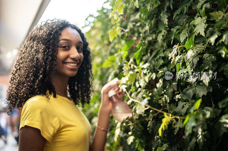 一个十几岁的女孩在户外浇灌植物的肖像