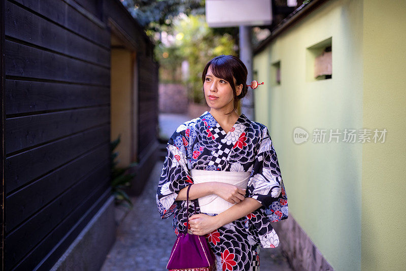 一位日本妇女走在一条狭窄的人行道上