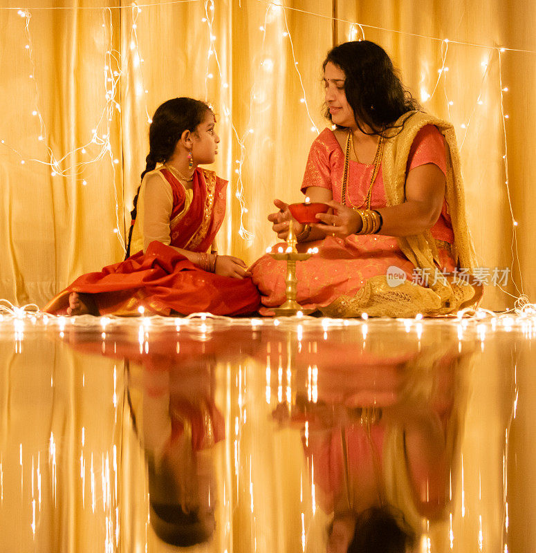 年轻的印度女孩和她的母亲拿着排灯节油灯
