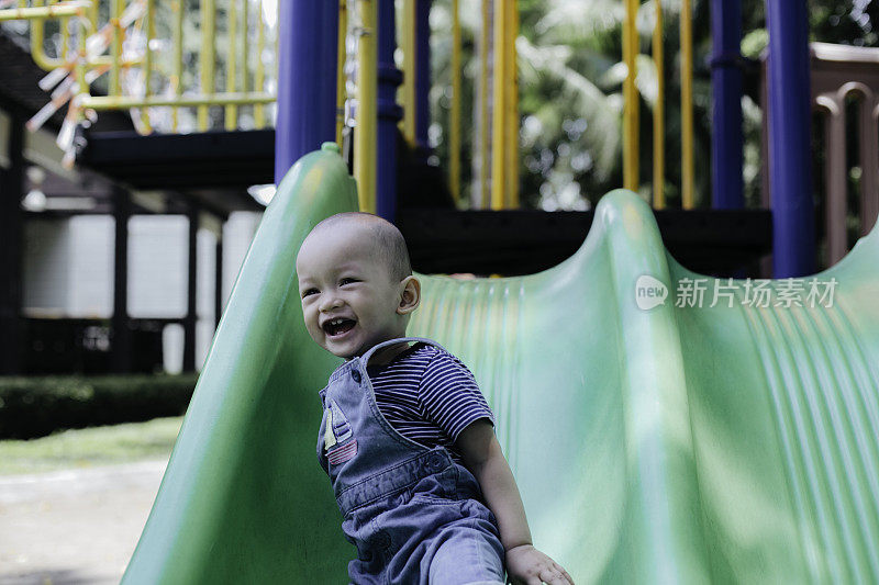 一个小男孩在操场上玩滑梯