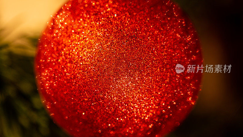 近距离的红色球装饰装饰在圣诞树上与闪闪发光的散景灯，冬天快乐的新年庆祝，